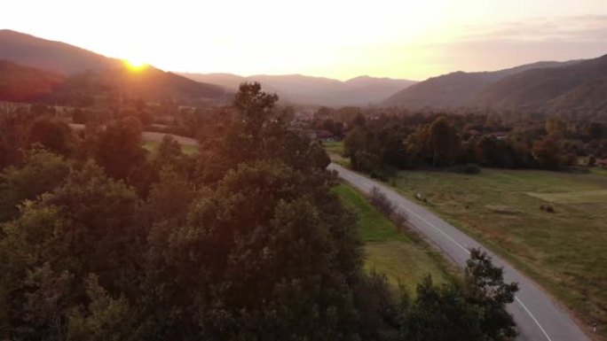 通往金色夏日日落的乡村之路-山里的日落，可以欣赏到山峦和村庄的景色-自然的舒缓场景