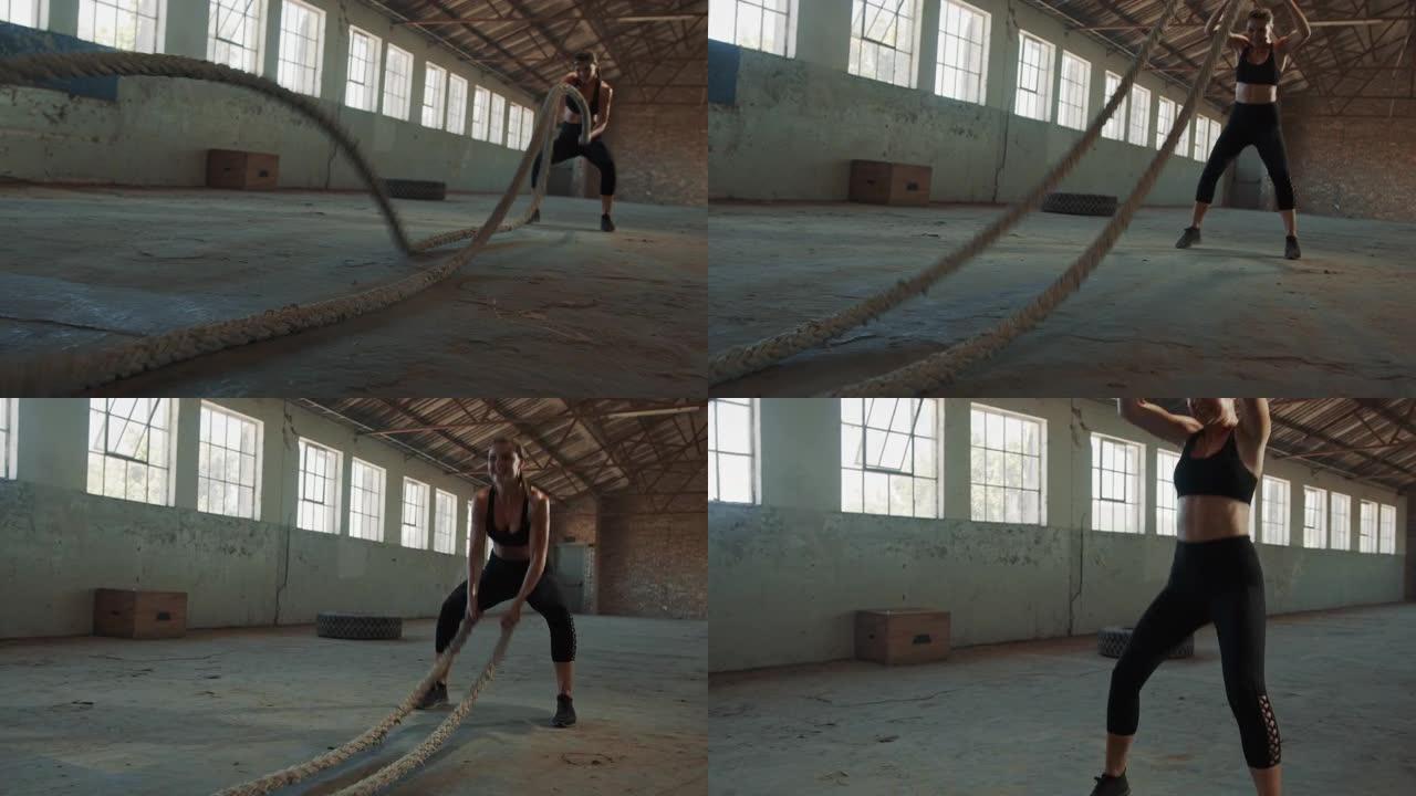 坚强的女人在旧仓库里用战斗绳锻炼