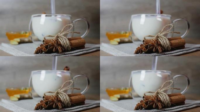在传统印度马萨拉柴茶的杯杯中混合蜂蜜。印度马萨拉柴茶香料茶与牛奶在质朴的木制背景，选择性聚焦，复制空