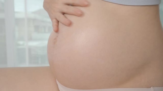 亚洲孕妇在孕妇腹部涂抹护肤油乳液，防止妊娠纹。