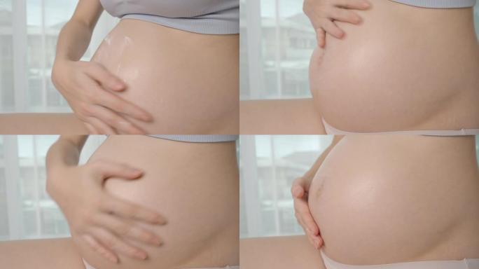 亚洲孕妇在孕妇腹部涂抹护肤油乳液，防止妊娠纹。