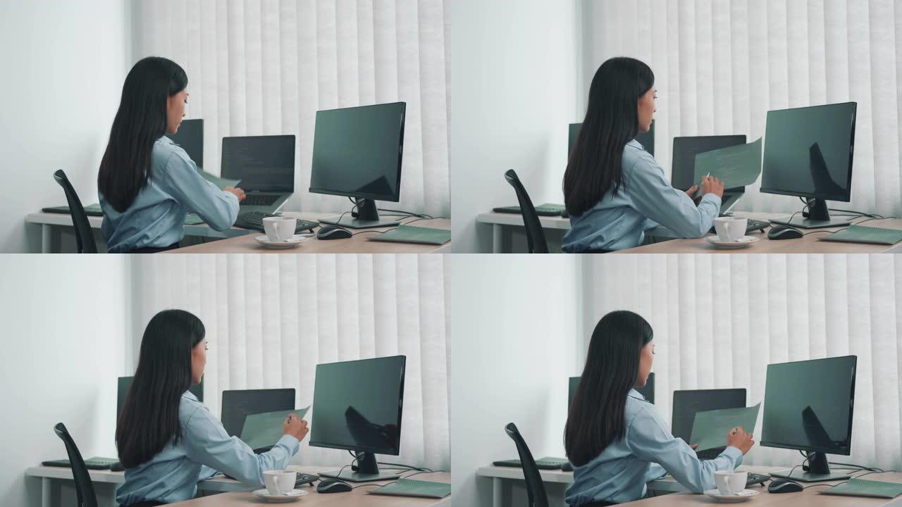 亚洲女性软件开发人员坐在电脑前看着屏幕上的电脑代码。
