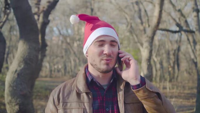 一个戴着新年帽子的男人正在打电话。打电话并祝圣诞快乐。