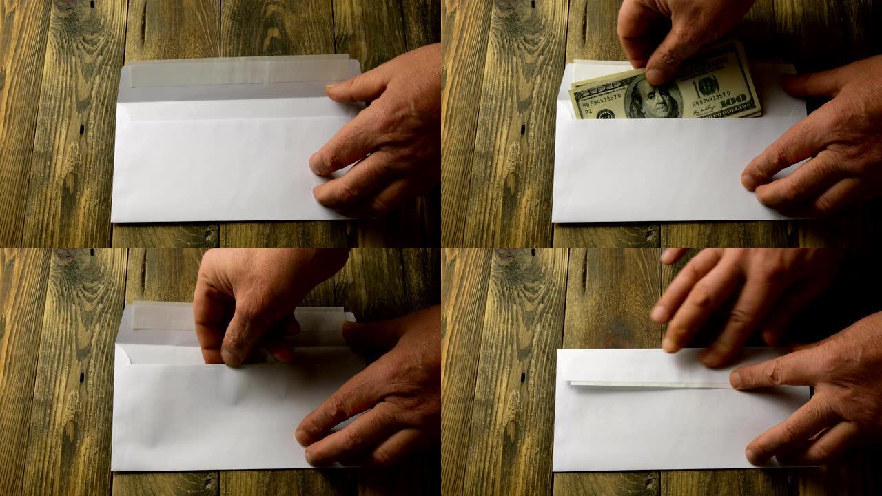有人用手把两张100美元现金装进棕色木桌上的白纸信封里。