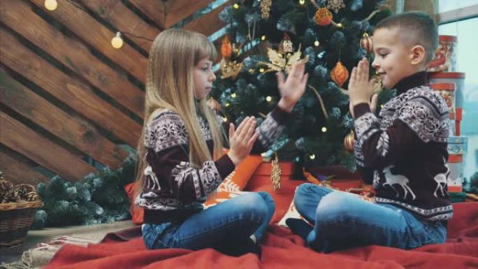 4k视频，男孩和女孩一起笑，一起玩乐，在木制圣诞节背景上玩鼓掌游戏。