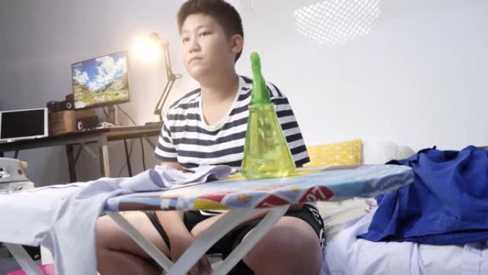 亚洲青春期男孩在夜间熨烫他的学生服，生活方式。