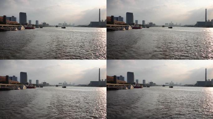 日落时在上海黄浦江上航行，从旅游船的船尾观看地标和船只，4k镜头，慢动作。