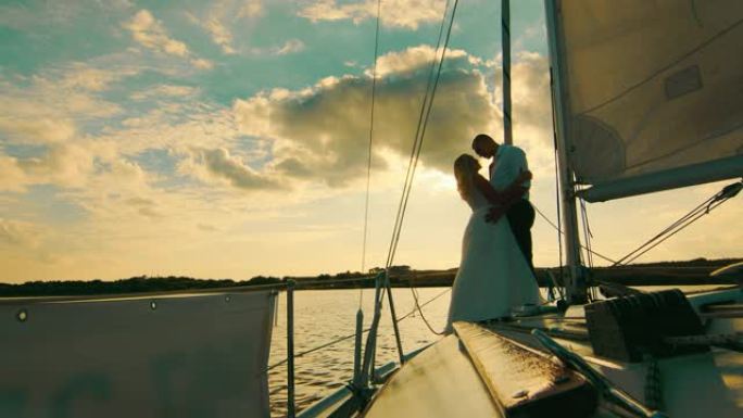 新婚夫妇站在泰坦尼 (Titani) 的帆船船头上。以美丽的日落为背景的新婚夫妇