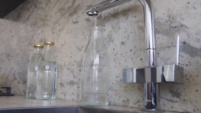 在家庭厨房里用过滤水重新装满玻璃瓶。