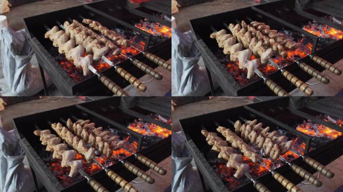 在街头美食节上，烤肉串上的鸡翅在烧烤上煮熟。