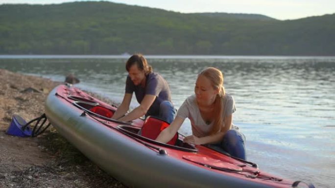 年轻的男人和女人准备他们的充气皮划艇在湖泊或海洋中划水。慢动作镜头