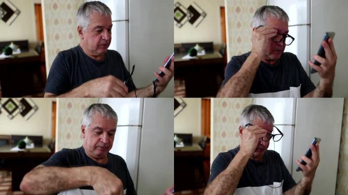 年长的男人在家里戴上老花镜检查智能手机设备