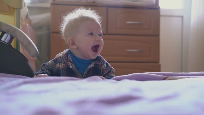 小男孩在儿童房的大床上玩粉色格子