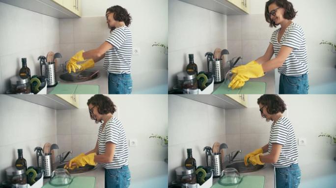 手持照片，一个穿着黄色橡胶手套的开朗女人洗碗