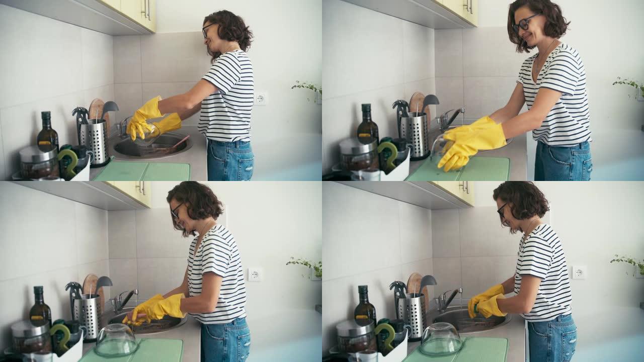 手持照片，一个穿着黄色橡胶手套的开朗女人洗碗