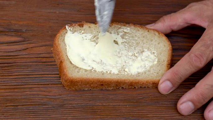 在面包上涂黄油。软黄油铺在酸面团面包上。碳水化合物，脂肪概念