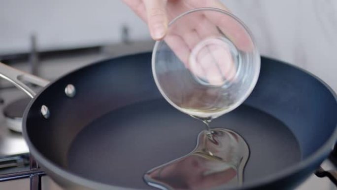 特写镜头将橄榄油倒入4k燃气灶上的预热锅中。
