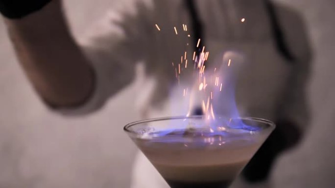 调酒师将肉桂粉撒在鸡尾酒的火焰上
