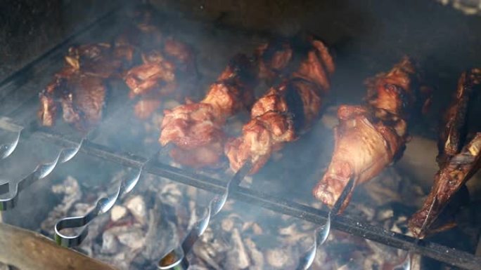 烧烤火盆的特写视图在金属串上烹饪大火鸡或鸡肉腿，在燃烧的煤上燃烧着火焰和烟雾。传统东欧烧烤派对家庭后