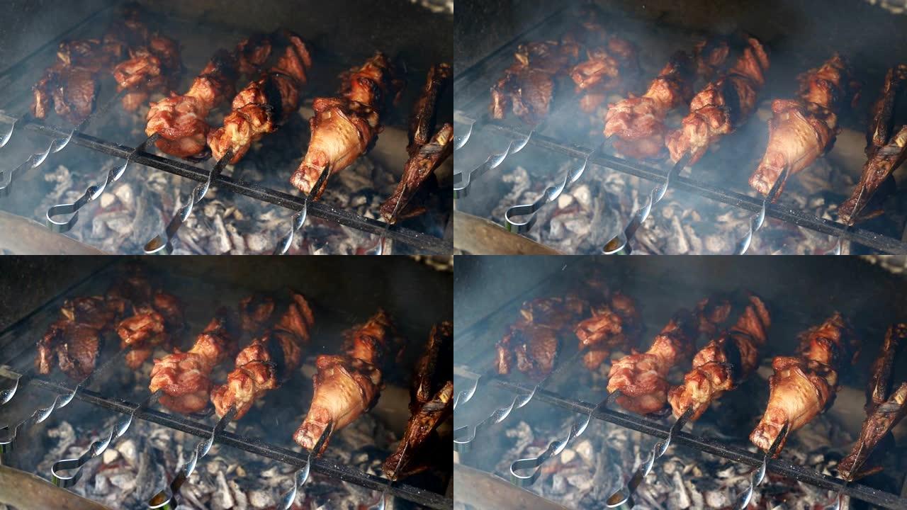 烧烤火盆的特写视图在金属串上烹饪大火鸡或鸡肉腿，在燃烧的煤上燃烧着火焰和烟雾。传统东欧烧烤派对家庭后
