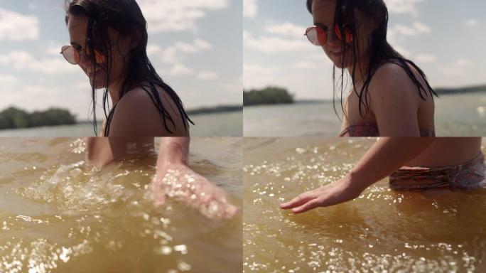 在炎热的天气里，一个女人站在湖中触摸水冷却的特写镜头
