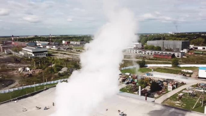 市区水泥生产厂烟囱冒烟的鸟瞰图。库存镜头。生态概念，蓝色多云天空背景下的工业企业