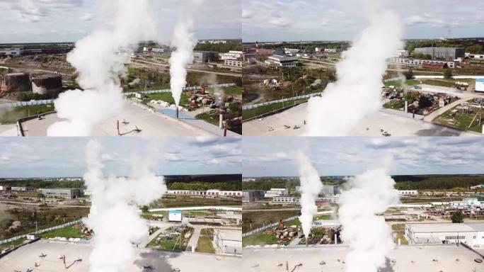 市区水泥生产厂烟囱冒烟的鸟瞰图。库存镜头。生态概念，蓝色多云天空背景下的工业企业