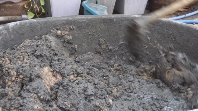 工人用铁铲在mortex桶中搅拌水泥混凝土 (浇注水泥砂石水)