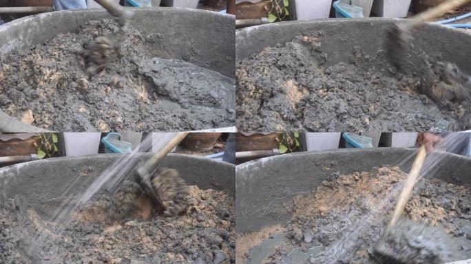 工人用铁铲在mortex桶中搅拌水泥混凝土 (浇注水泥砂石水)
