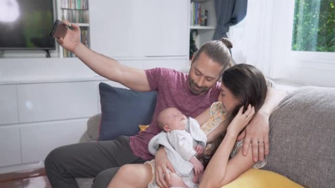 4k微笑的白人男子使用智能手机拍摄他的妻子和正在睡觉的新生儿子的家庭视频。父亲用爱亲吻母亲和可爱的婴