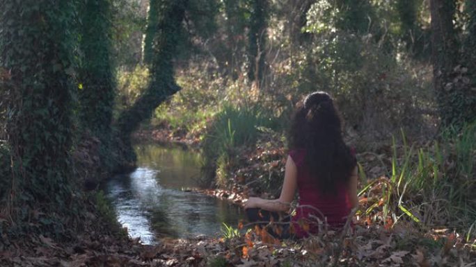 4k视频，成年女性在丛林中通过流水进行瑜伽练习