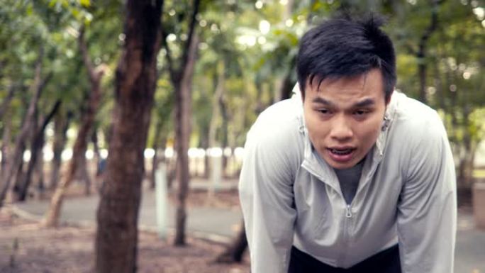 英俊的亚洲男子运动员跑步者在森林里进行户外运动训练后筋疲力尽地休息。