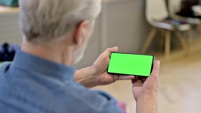老人在绿色模拟屏幕智能手机上观看视频