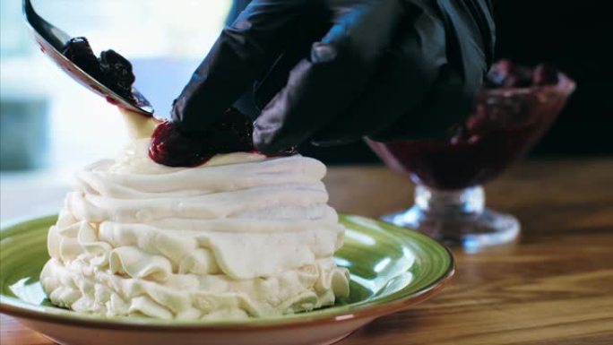 厨师用奶油和樱桃果酱烹饪蛋白酥皮蛋糕。