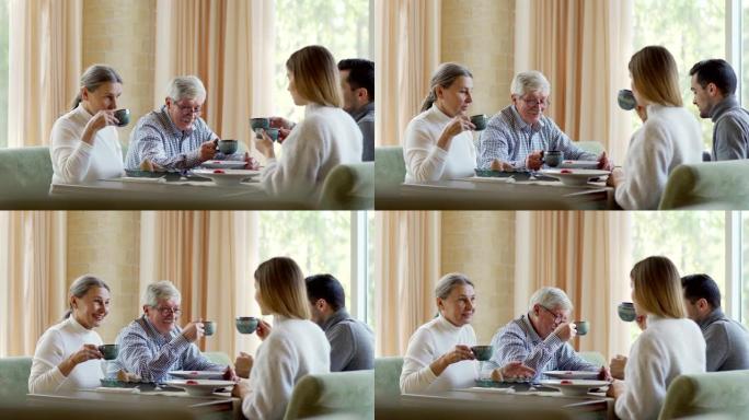 年轻夫妇和老年夫妇的侧视图跟踪照片，两代家庭在餐厅共进晚餐。年迈的父母和他的儿子与妻子用茶杯敬酒