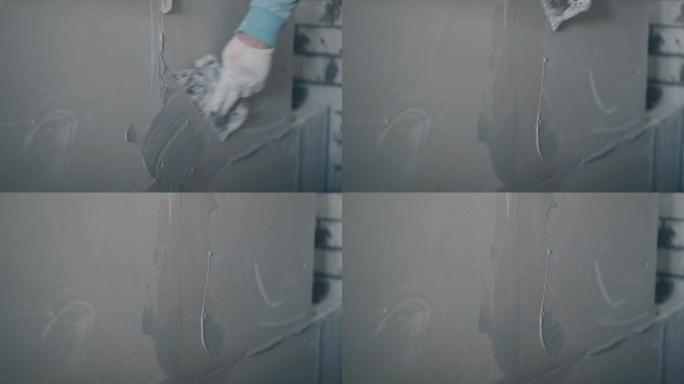 画家手臂握着油灰刀，用底漆涂抹墙壁
