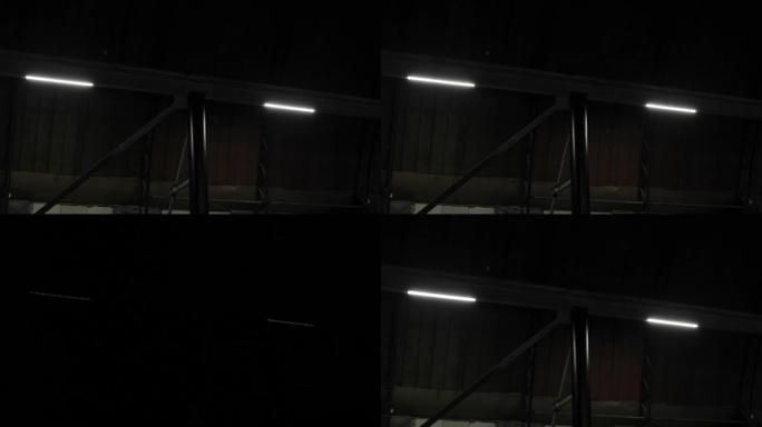 金属梁隔板上的led灯在工厂的黑暗房间，无窗户的机库，车间部门中关闭。工业制造区停电、网络电气短路