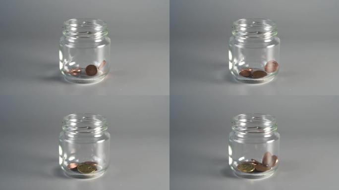 硬币落入玻璃罐。财务储蓄的概念。