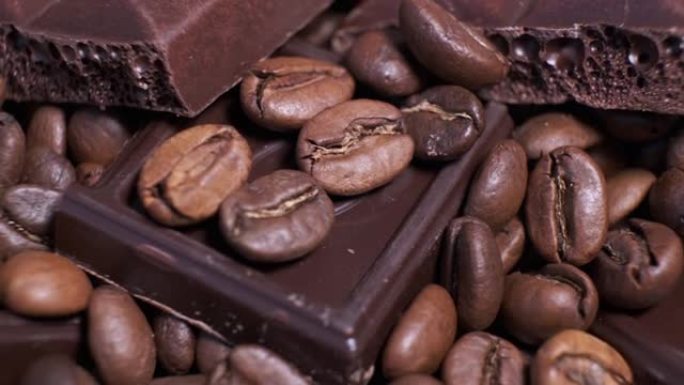 旋转桌上深色烘焙咖啡豆和巧克力的特写镜头。芳香的咖啡粒和甜的巧克力块正在转动。