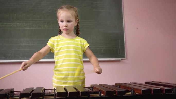 一个小女孩在音乐课上演奏木琴。4k