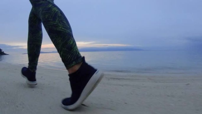 早上在海滩上跑步锻炼的女人。慢动作
