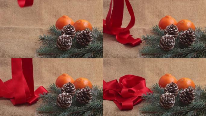 新年的组成，橘子，松果和新年树的树枝被解雇。红丝带慢慢落在框架中的桌子上。