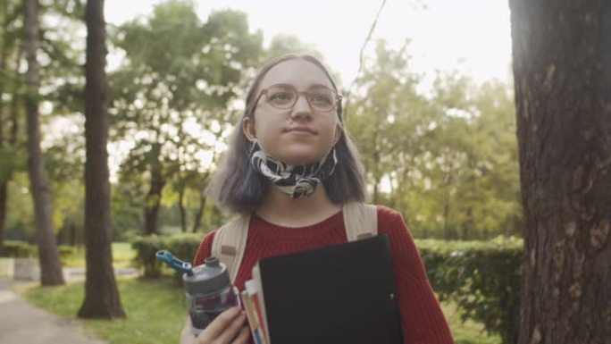在大学或大学校园附近学校附近的可重复使用的防护口罩中的年轻青少年学生
