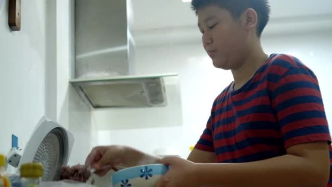 亚洲男孩把米饭放在碗里摆桌子，准备吃。