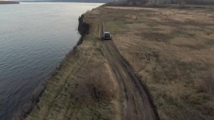 跨界车沿着秋天的田野鸟瞰图骑在海边。旅游越野越野车汽车沿着海边的乡村田野行驶。无人机视图越野车在海洋