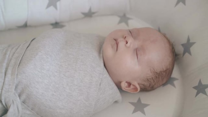 可爱的睡懒觉婴儿儿子裹在薄纱襁褓中