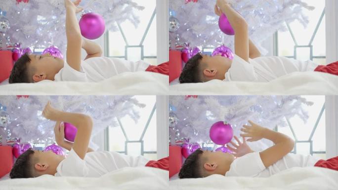 视频的小孩躺在圣诞树下，玩粉红色的球.4k，气氛，球，球，卧室，庆祝，欢快，童年，圣诞节，冷，颜色，