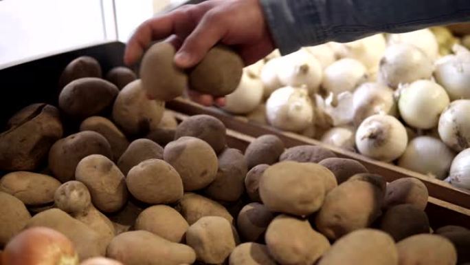 男性双手选择最佳形状的土豆，然后放入透明的塑料包装袋中。购物的人选择漂亮的土豆会添加到包装中。特写