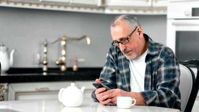 微笑着戴眼镜的成熟大胡子男人使用智能手机聊天享受咖啡休息