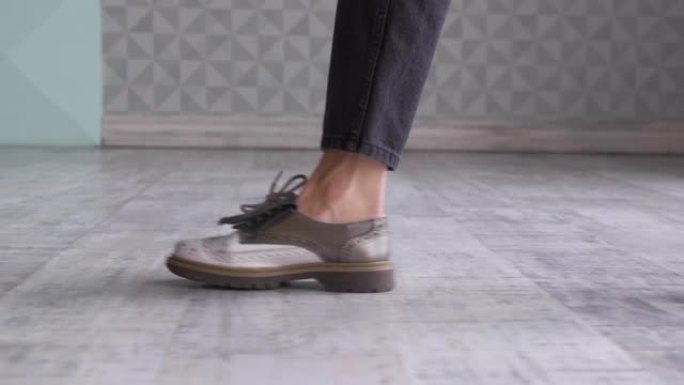 女人穿着鞋子的脚走在地毯地板上的侧视图。穿着米色鞋子的女性腿在长廊上行走的特写